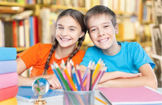 Portrait of two diligent girls looking at camera at workplace with schoolboys on background