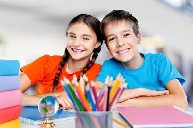 Photo portrait of two diligent girls looking at camera at workplace with schoolboys on background