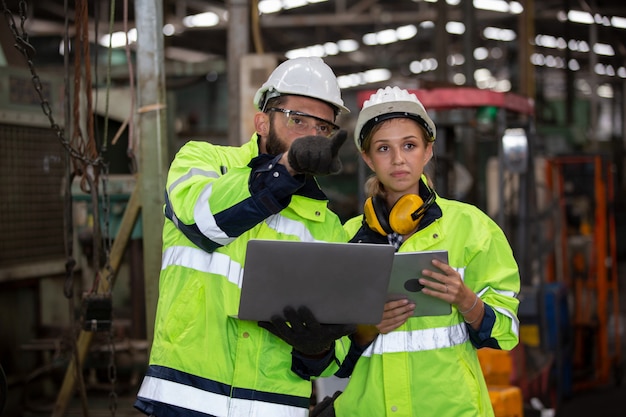 Photo portrait of two engineer discussing on project against machine in factory environment,