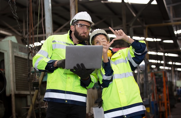 Portrait of two Engineer discussing on project against machine in factory environment,