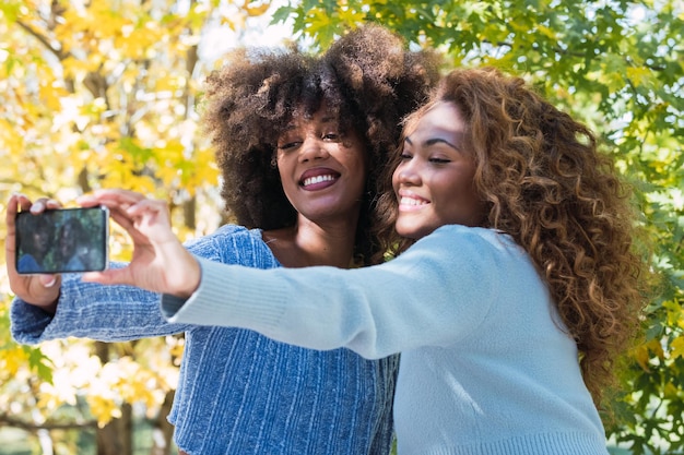 Portrait of two female afro american friends smiling while taking selfie