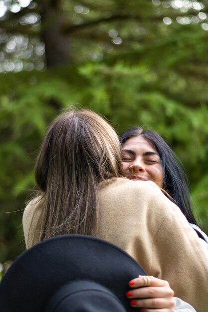 Portrait of two female friends standing hugging on the grass Rear view of two female friends hugging on the grass Girls friendship concept