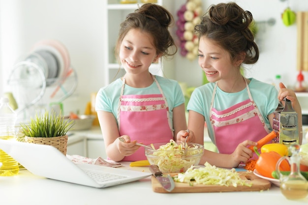 Portrait of two girls sisters in the kitchen cook