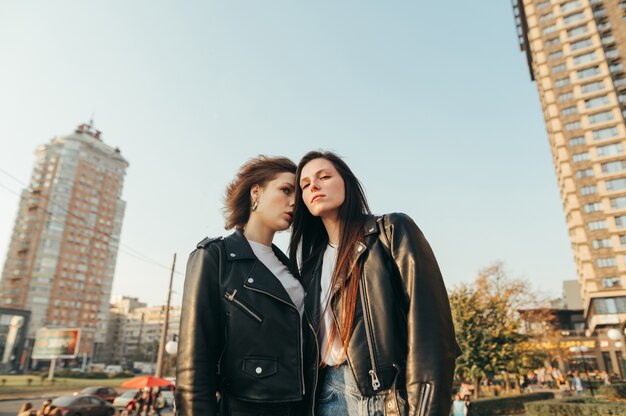 Portrait two girls in street clothes standing on grass on cityscape