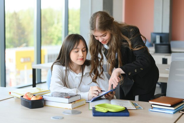 Photo portrait of two girls at workplace with books school education