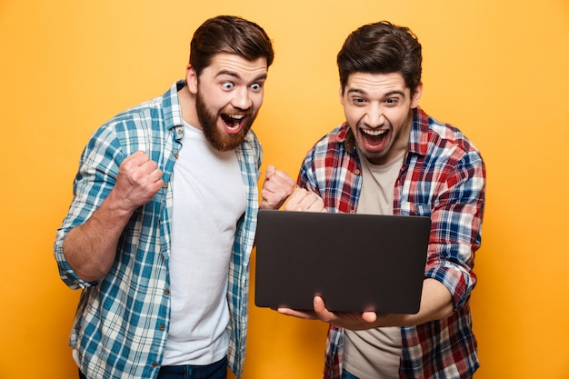 Portrait of a two happy young men looking at laptop