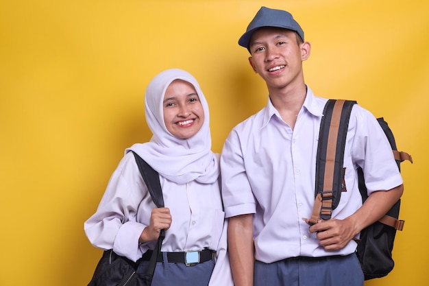 Portrait of two Indonesian high school students in white and grey uniform isolated on yellow backgro