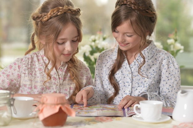 Portrait of two little girls reading magazine