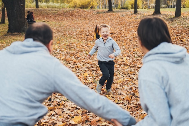 Portrait of two little kids running into their parents hug mother and father playing with kids outdo