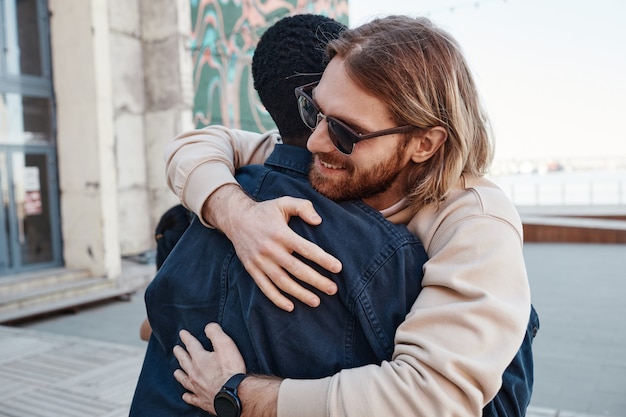 Photo portrait of two male friends embracing outdoors in urban city setting, copy space