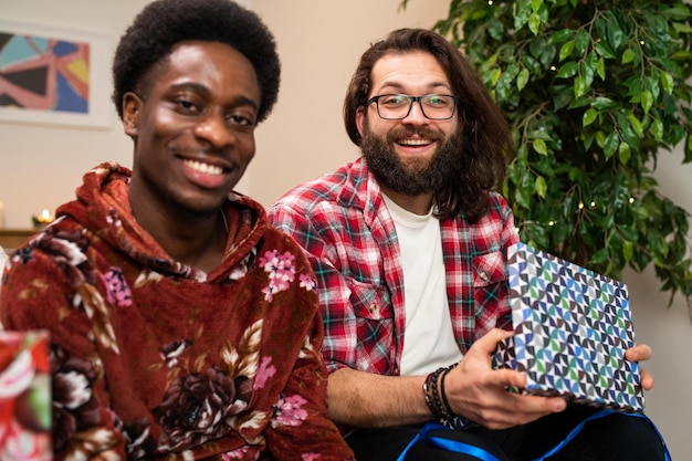 Portrait of two men exchanging christmas gifts smiling friends spend the evening together
