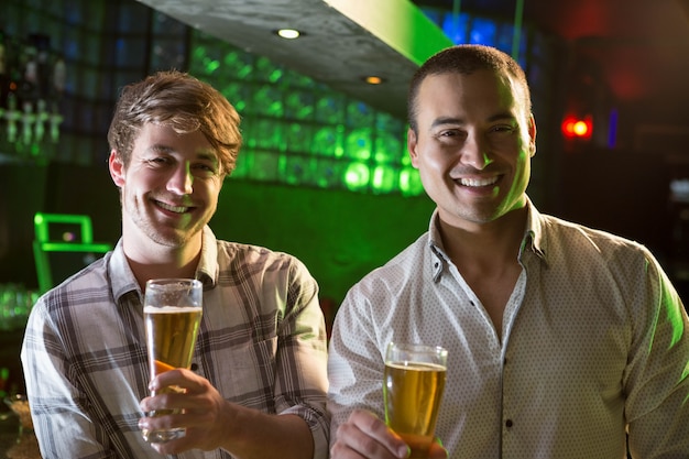 Портрет двух мужчин, имеющих пиво на барной стойкой в баре
