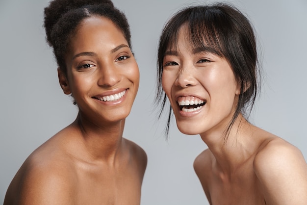 Portrait of two multinational half-naked women looking at camera and laughing 