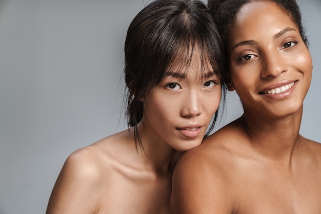 Portrait of two multinational half-naked women posing together and looking at camera 