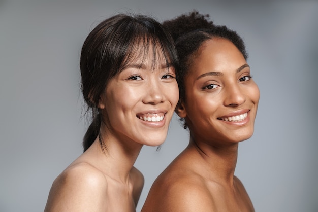 Portrait of two multinational half-naked women posing together and smiling 