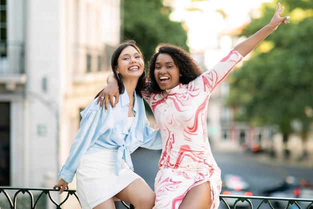 Photo portrait of two multiracial female friends laughing together outdoors