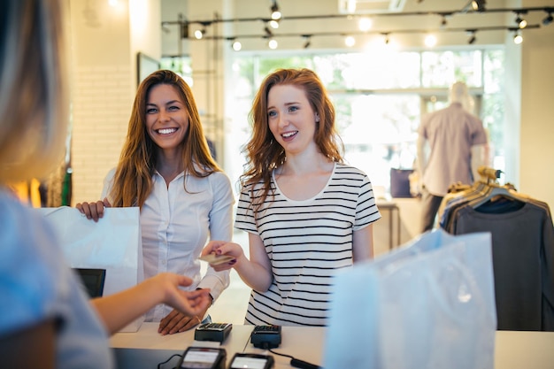 Portrait of two satisfied woman paying with a credit card on the cash register in the store.