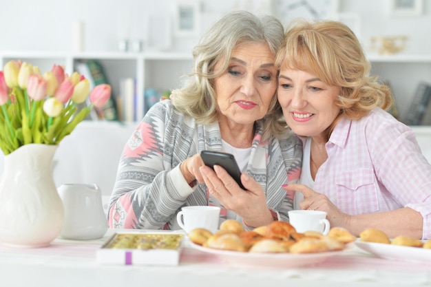 Portrait of two senior women using smartphone at home