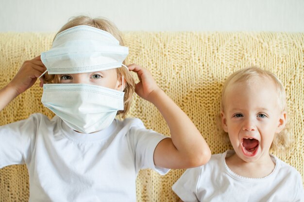 Portrait of two sisters putting on medical protective masks the older sister helps the younger