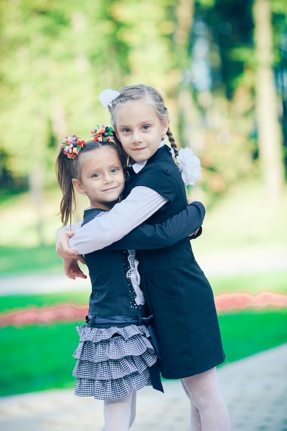 Portrait of two sisters standing on the street hugging and looking at the camera with smiles and happy faces