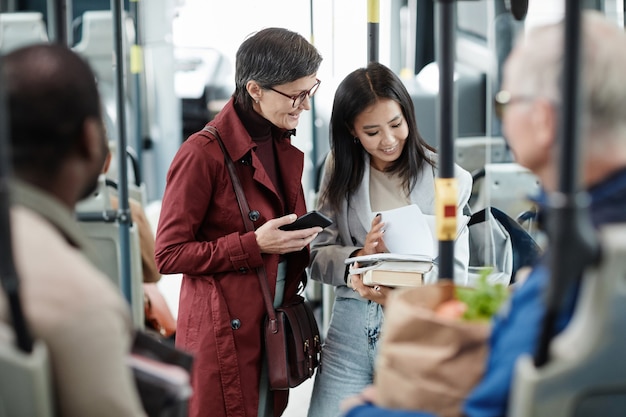 市内の公共交通機関で旅行中にバスでおしゃべりする2人の笑顔の女性の肖像画、コピースペース