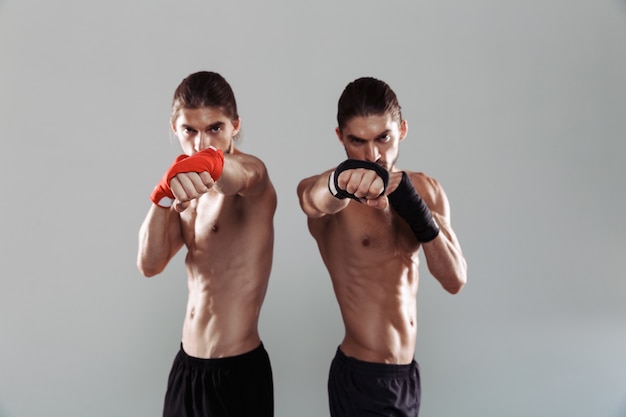 Portrait of a two strong muscular shirtless twin brothers