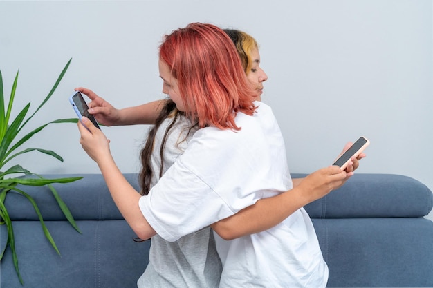 Ritratto due ragazze adolescenti stanno abbracciando e guardando nel telefono. il concetto di dipendenza dei bambini adolescenti od gadget e social network.