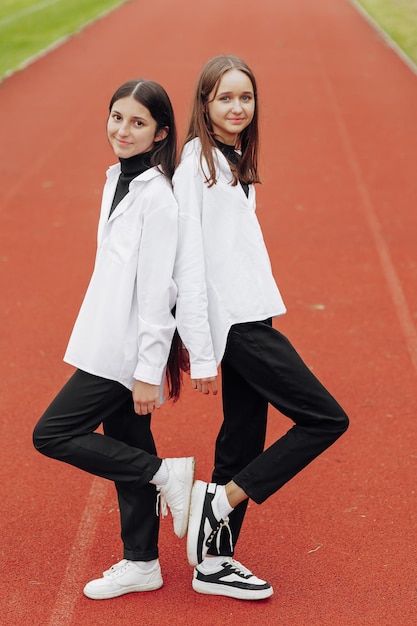 Portrait of two teenage girls in casual clothes sitting in a stadium and posing looking at the camera Concept of friendship A moment of happiness