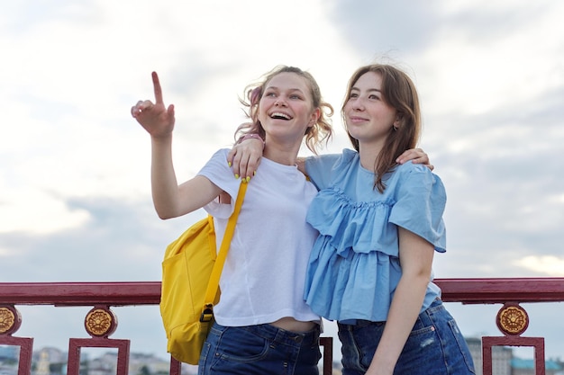 Ritratto di due amici di ragazze adolescenti che camminano e parlano sul ponte pedonale in una giornata di sole estivo. amicizia, stile di vita, gioventù, adolescenti