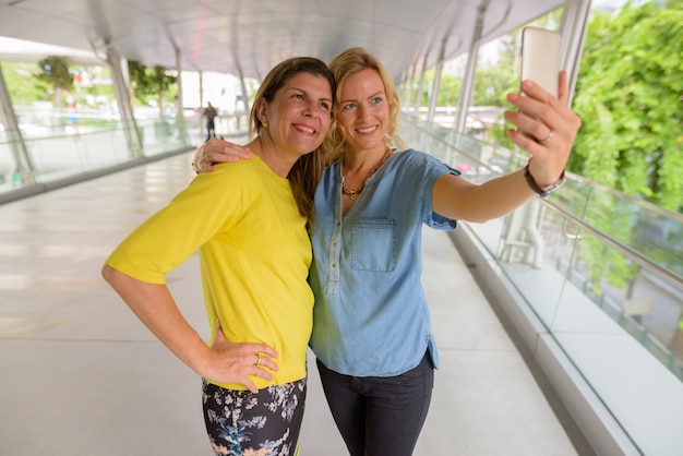 Portrait of two woman together outdoors taking selfie with mobile phone