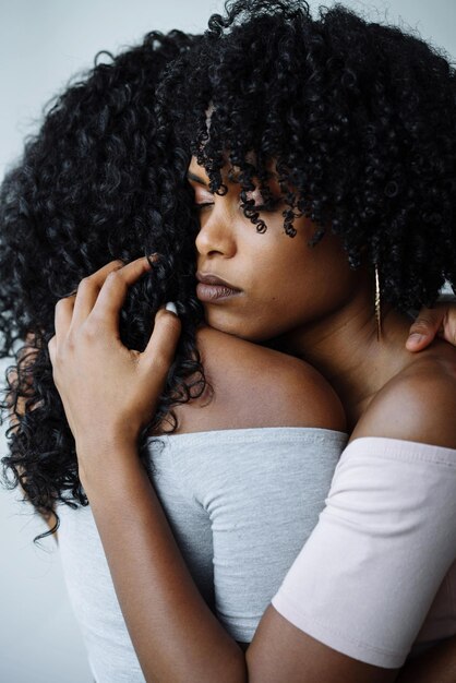 Photo portrait of two women of color hugging each other