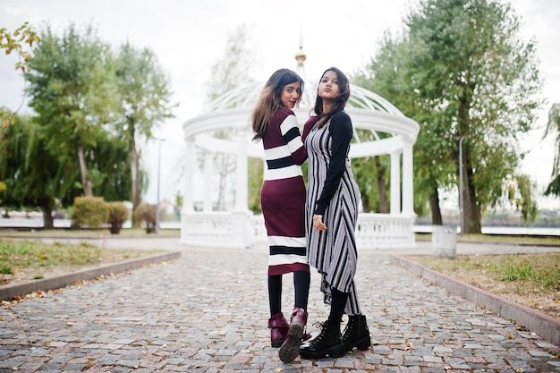 Portrait of two young beautiful indian or south asian teenage girls in dress background white temple arch