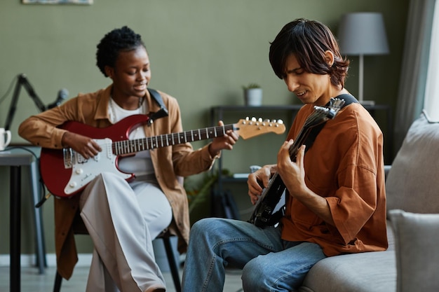 Photo portrait of two young musicians playing guitars together and singing in music studio with muted gree