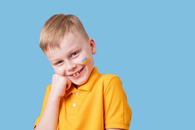 Portrait of a Ukrainian boy with a drawing flag on his cheek cheerfully smiling at the camera