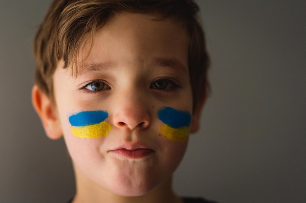 Portrait of a ukrainian boy with a face painted with the colors of the ukrainian flag