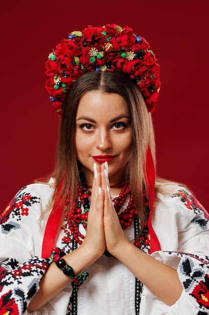 Portrait of ukrainian woman in traditional ethnic clothing and floral red wreath on viva magenta studio background Ukrainian national embroidered dress call vyshyvanka Pray for Ukraine