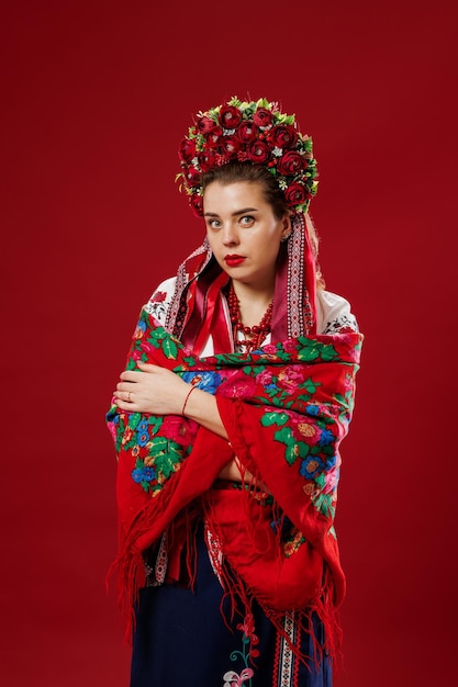 Portrait of ukrainian woman in traditional ethnic clothing and floral red wreath on viva magenta studio background Ukrainian national embroidered dress call vyshyvanka Pray for Ukraine