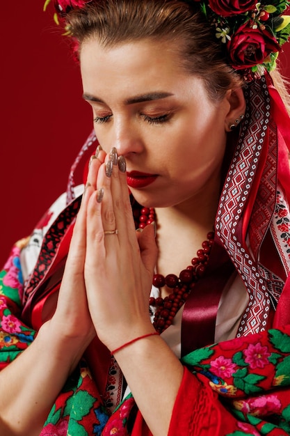 Portrait of ukrainian woman in traditional ethnic clothing and floral red wreath on viva magenta studio background Ukrainian national embroidered dress call vyshyvanka Pray for Ukraine