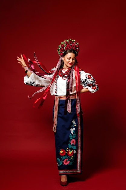 Portrait of ukrainian woman in traditional ethnic clothing and floral red wreath on viva magenta studio background Ukrainian national embroidered dress call vyshyvanka Pray for Ukraine