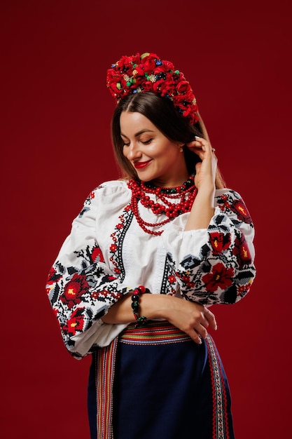 Portrait of ukrainian woman in traditional ethnic clothing and floral red wreath on viva magenta studio background Ukrainian national embroidered dress call vyshyvanka Pray for Ukraine