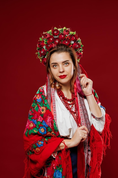 Portrait of ukrainian woman in traditional ethnic clothing and floral red wreath on viva magenta studio background Ukrainian national embroidered dress call vyshyvanka Pray for Ukraine