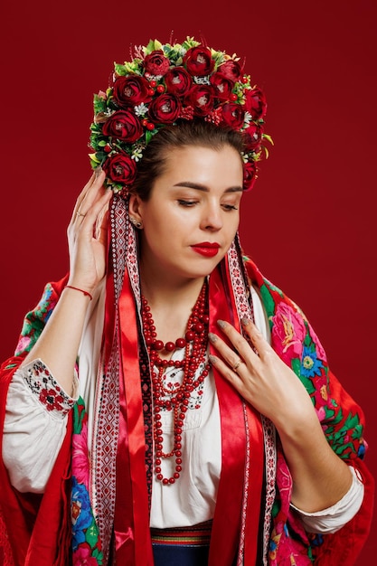 Portrait of ukrainian woman in traditional ethnic clothing and floral red wreath on viva magenta studio background Ukrainian national embroidered dress call vyshyvanka Pray for Ukraine