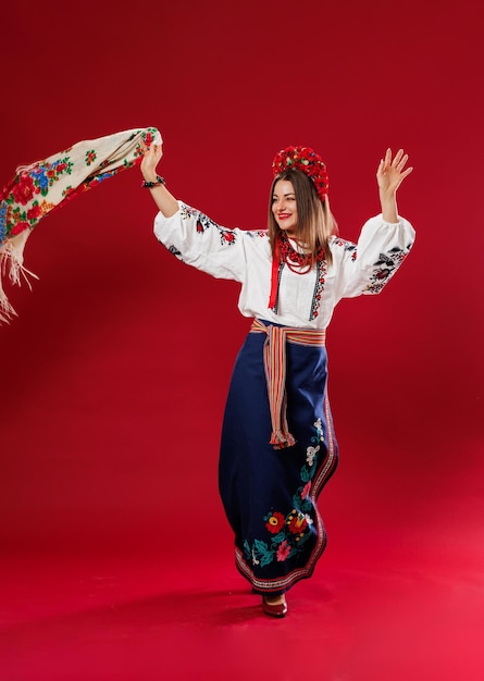 Portrait of ukrainian woman in traditional ethnic clothing and floral red wreath with handkerchief on viva magenta studio background Ukrainian national embroidered dress call vyshyvanka