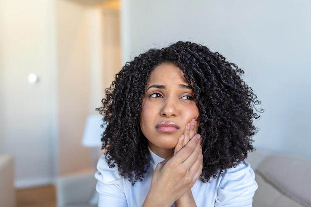 Portrait of unhappy AfricanAmerican woman suffering from toothache at home Healthcare dental health and problem concept Stock photo