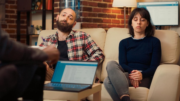 Photo portrait of unhappy couple attending therapy session with specialist, trying to solve relationship problems. talking to psychologist about marriage counseling or divorce. handheld shot.