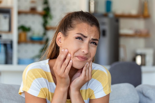 Portrait of unhappy young woman suffering from toothache at\
home healthcare dental health and problem concept