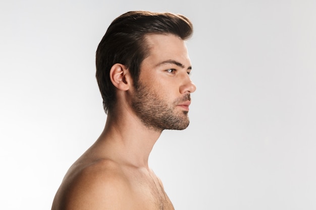 Portrait of unshaven half-naked man posing and looking aside isolated on white