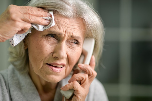 Portrait of upset senior woman calling doctor