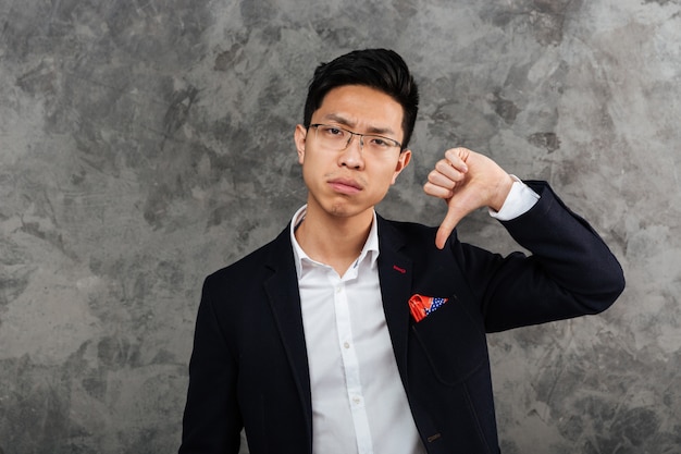 Portrait of an upset young asian man dressed in suit