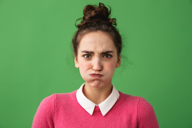 Photo portrait of an upset young woman standing isolated over green